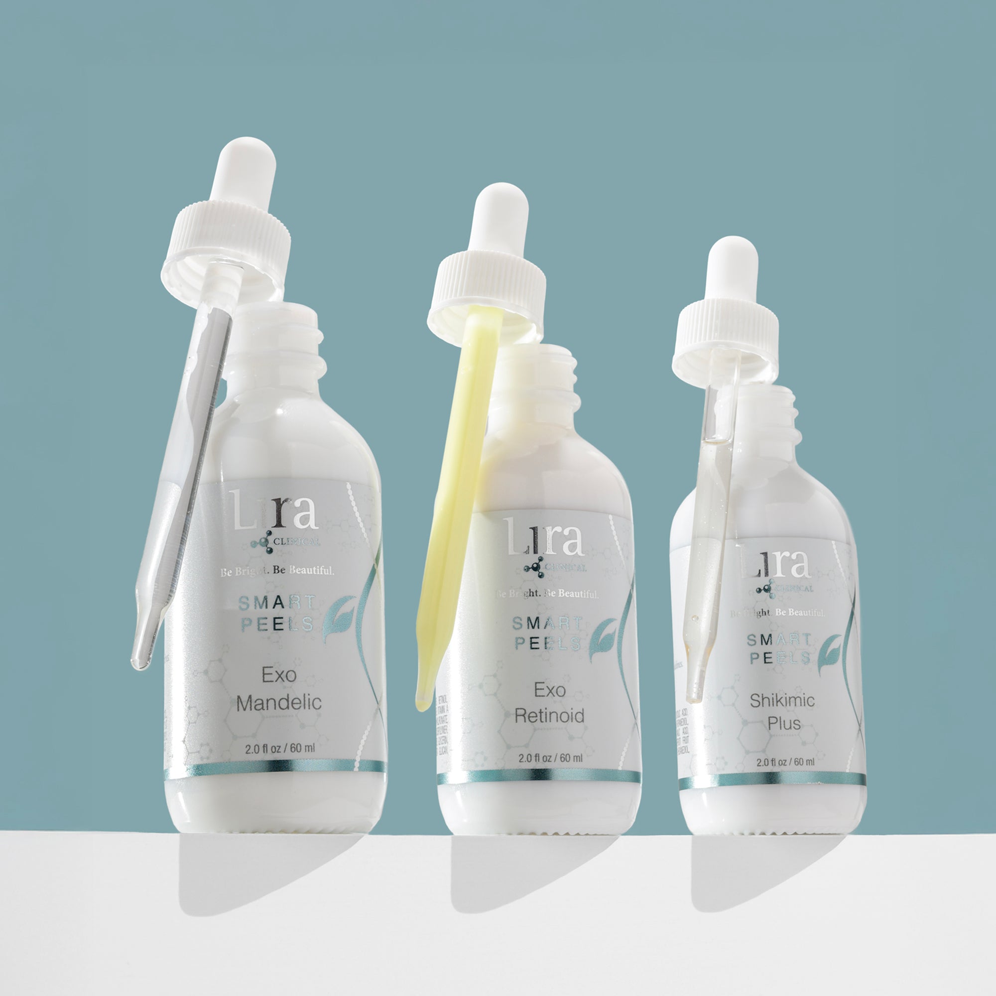 Group shot of three white bottles white lids silver and light blue text DNA on bottles SMART PEELS Exo Mandelic Exo Retinoid Shikimic Plus